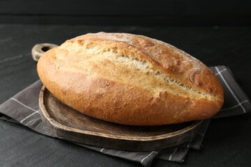 Loaf of bread on black textured table, closeup