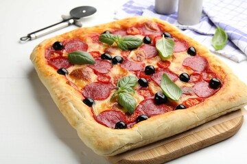 Tasty homemade pizza and cutter on white table, closeup