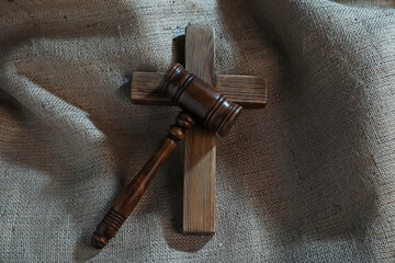 Judge's gavel and wooden cross on burlap fabric, top view
