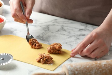 Woman making ravioli bolognese at white marble table, closeup