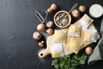 Uncooked ravioli, mushrooms and sauce on black table, flat lay. Space for text