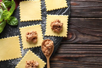 Making ravioli bolognese at wooden table, flat lay. Space for text