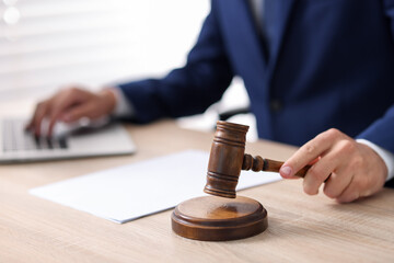 Judge with gavel working at desk indoors, closeup