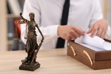 Judge working and Lady Justice figure on desk indoors, selective focus