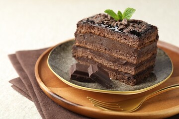 Piece of delicious chocolate cake with mint on table, closeup