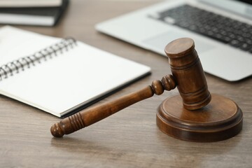 Laptop, judge's gavel and notebook on wooden table in office, closeup