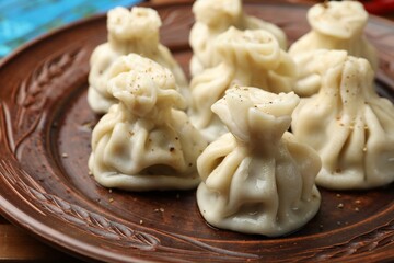 Many delicious khinkali on plate, closeup view