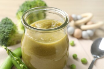 Baby food. Tasty puree in glass jar and ingredients on table, closeup