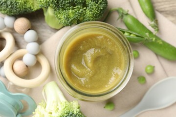 Baby food. Tasty puree in jar, ingredients, pacifier and teether on table, flat lay