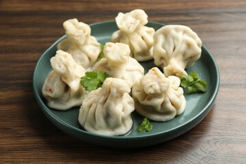 Delicious khinkali with cilantro on wooden table, closeup