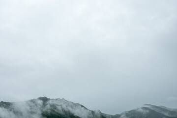 群馬県みどり市で撮影した雨の日の霧が漂う山稜線と広大な灰色の空のミニマル風景（コピー用空白スペース有）
