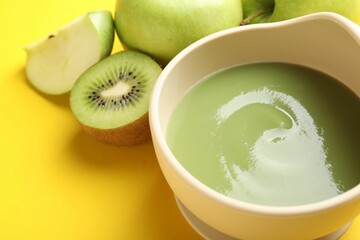 Baby food. Tasty puree in bowls and different ingredients on yellow background, closeup
