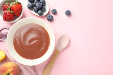 Baby food. Tasty puree in bowl, pacifier and ingredients on pink background, flat lay. Space for...