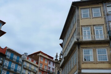 Historic buildings with colorful facades rise towards a cloudy sky in Porto