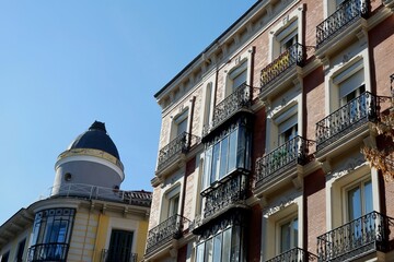 Historic buildings with intricate balconies and unique rooftops stand against a clear blue sky