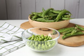 Fresh ripe green peas on white wooden table