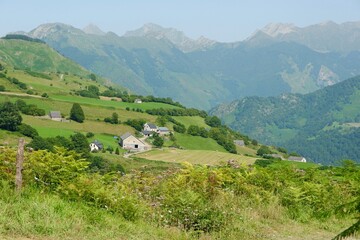 Lush green hills cradle small houses, showcasing a peaceful rural landscape in the mountains
