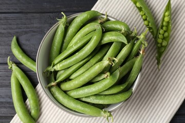 Fresh ripe green peas on black wooden table, flat lay