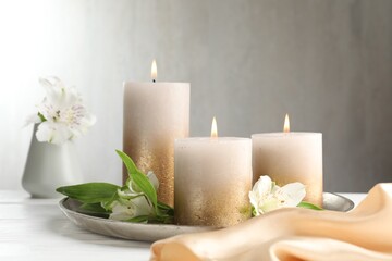 Burning candles and beautiful flowers on white table. Space for text