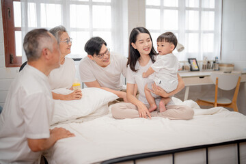 Fototapeta premium Family gathered in a cozy bedroom enjoying quality time with a toddler, sharing smiles and laughter during the day