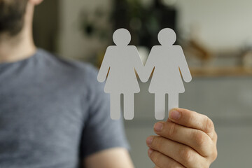 Image of two paper figures holding hands, representing love, partnership, and commitment.