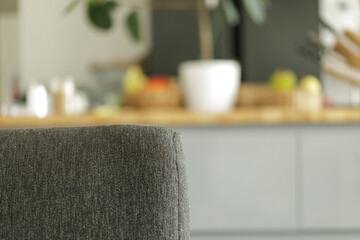Close-up of a grey fabric chair back, blurred kitchen background. Modern interior design.