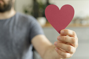 Close-up of a man's hand gently holding a red heart.  Perfect for love, Valentine's Day, or...