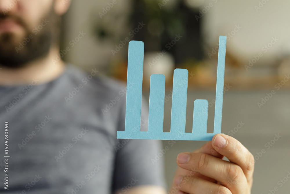 Fototapete a man holds a simple bar graph illustrating upward trending data, symbolizing progress and success.