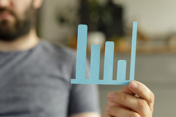 A man holds a simple bar graph illustrating upward trending data, symbolizing progress and success.