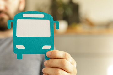 Close-up of a man holding a teal paper bus cutout.  Public transportation concept.