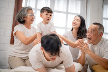 Family gathering in a bright room with joyful interactions among grandparents, parents, and child during a fun playtime moment