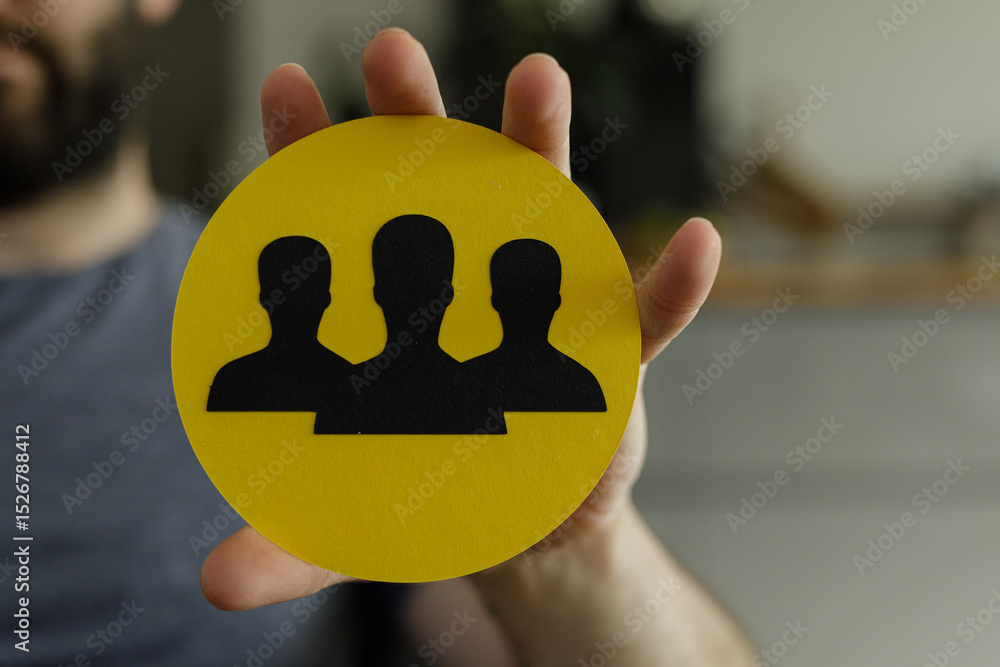 Poster image of a hand holding a yellow circle with three black silhouettes representing teamwork and colla
