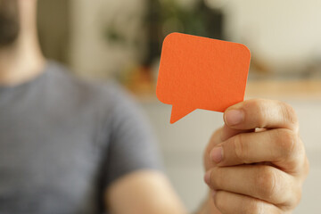 A man holds an orange speech bubble, representing communication and feedback.