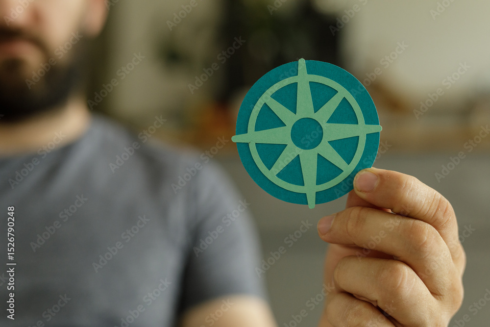 Poster a man holds a paper compass, symbolizing guidance, direction, and finding your way.