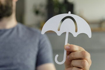 Image of a person holding a paper umbrella, symbolizing protection, insurance, or safety.