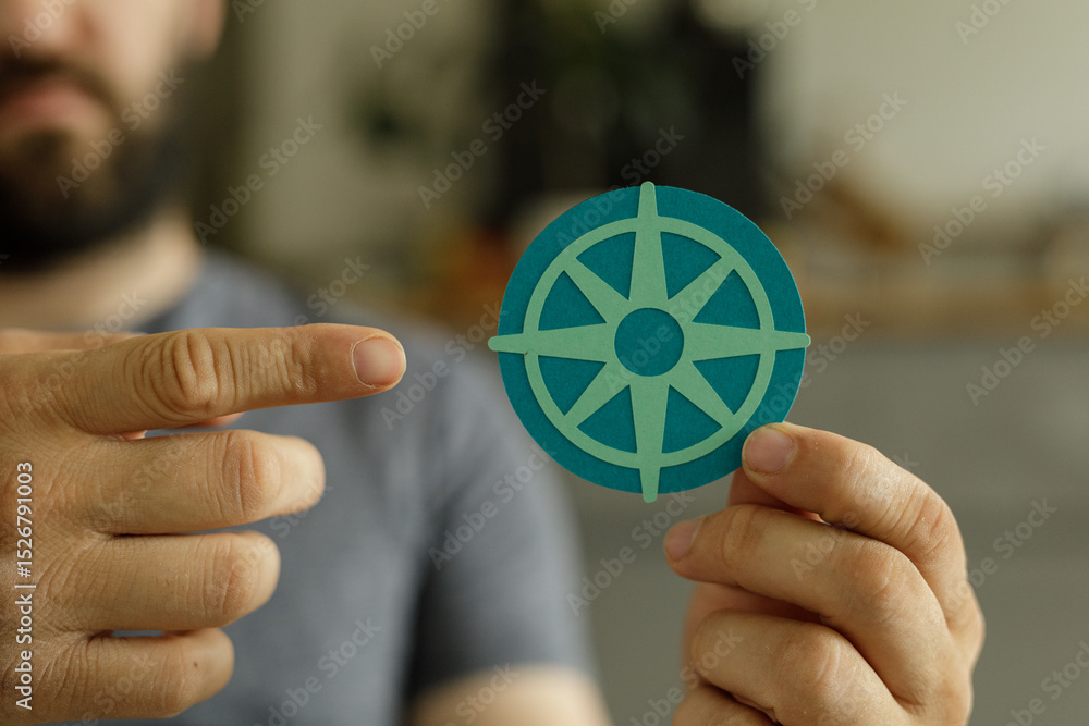 Poster close-up of a man's hands holding a compass symbol, representing guidance and direction.