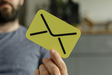 Close-up of a man holding a yellow card with an email icon.  Perfect for communication, message,...