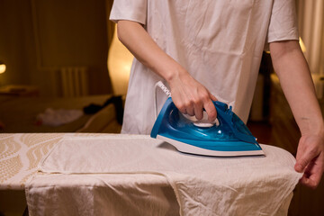 A person meticulously ironing clothes at home, ensuring all garments are neat and well cared for