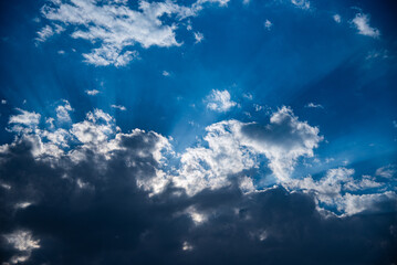 Obraz premium The photo shows a dramatic sky where bright sun rays break through thick clouds. The combination of light and shadow creates a striking and inspiring scene.