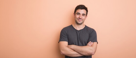 The confident young man smiles with arms crossed against a pastel wall.