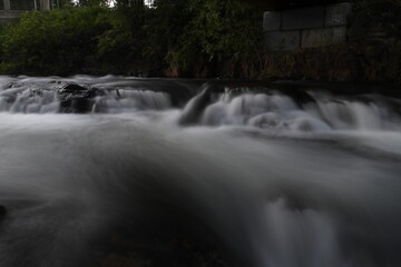 Low angle flowing creek over rocks and dark green foliage in background