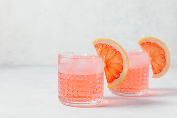 A refreshing negroni rosa cocktail served in a textured glass with ice, garnished with a slice of...