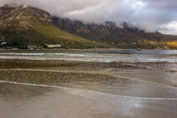 View towards the Chapmans Peak from the beach at Hout Bay, with the distant mountains shrouded in the incoming fog at the end of the day.