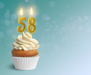 Yummy cupcake with burning number shaped candles on light blue gradient background, space for text....