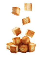 Delicious crispy croutons falling onto pile on white background