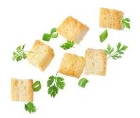 Delicious crispy croutons, green onion and parsley flying on white background