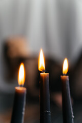 Mysterious young woman in black lace gazes intensely through candlelight, evoking elegance and gothic allure