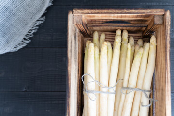 Ready to be cooked crisp white asparagus piled in a gray wooden crate
