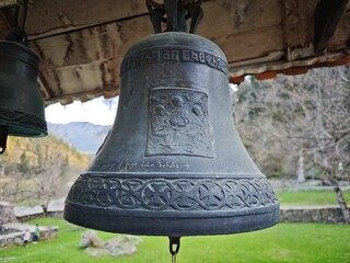 Old bronze bell with religious engravings and inscriptions hanging in a monastery