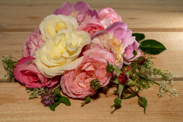 Bouquet of pink roses, peonies on a light wooden background.
